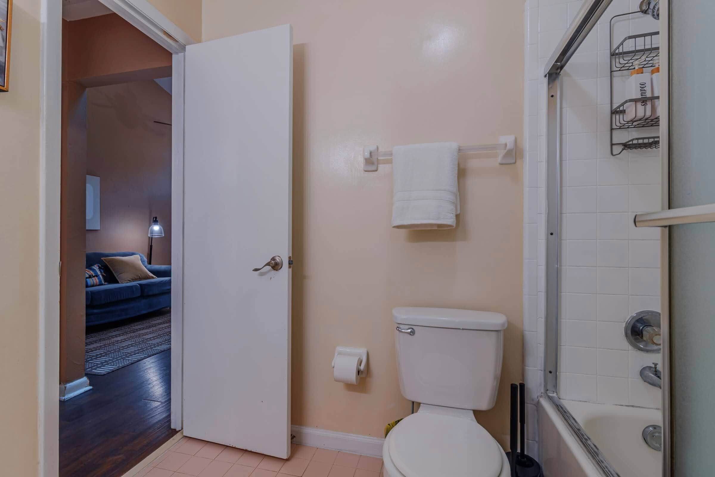 A bathroom with a toilet, a towel rack, and a shower area.
