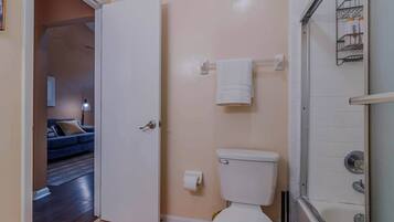 A bathroom with a toilet, a towel rack, and a shower area.