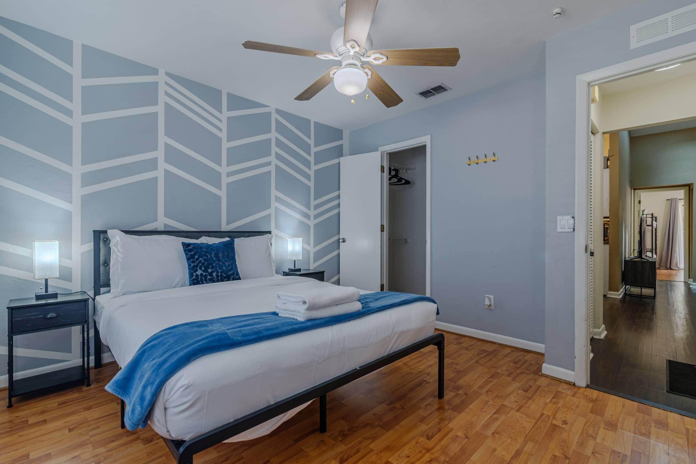 Ein Schlafzimmer mit Bett, Nachttischen, Deckenventilator und Kleiderschrank.