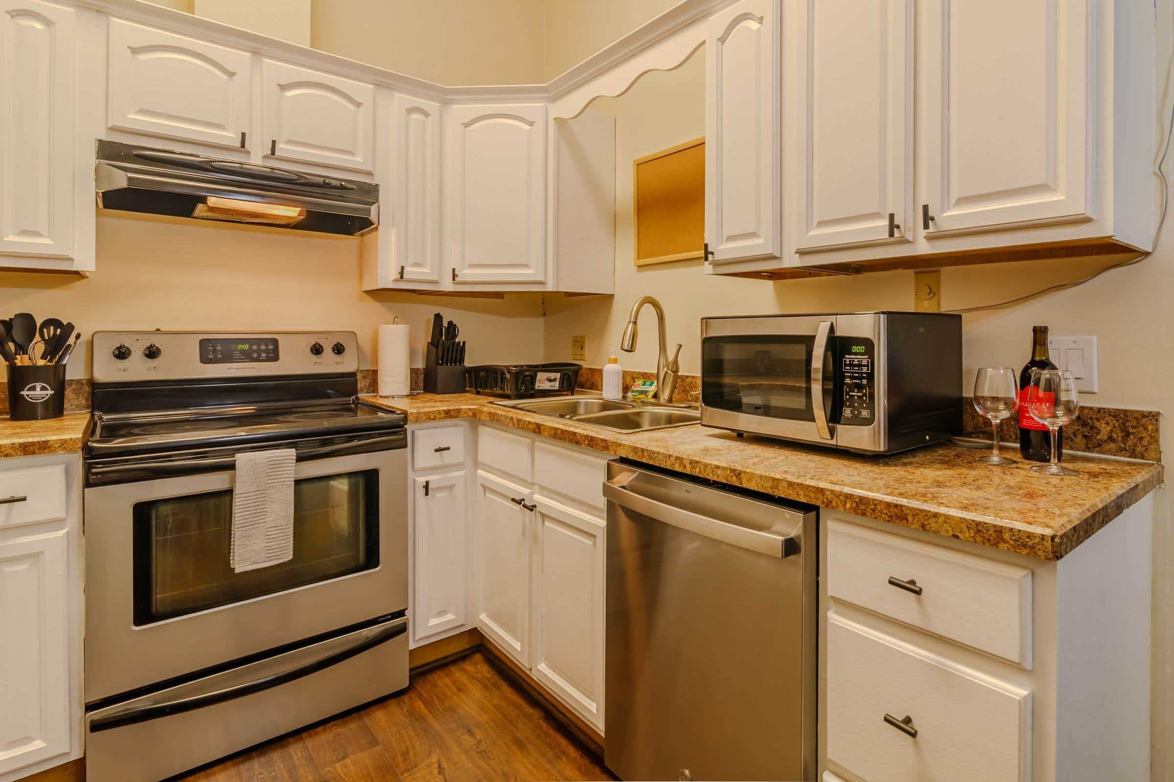 A kitchen with white cabinetry, stainless steel appliances, a granite countertop, and a dishwasher.
