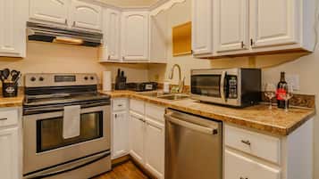 A kitchen with white cabinetry, stainless steel appliances, a granite countertop, and a dishwasher.