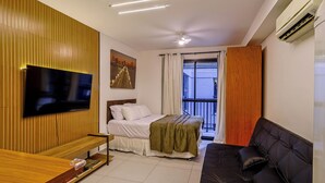 Un dormitorio moderno con cama, televisor montado en la pared, ventilador de techo y aire acondicionado.
