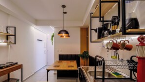 Una cocina moderna con una mesa de comedor de madera, una lámpara colgante y una cafetera.