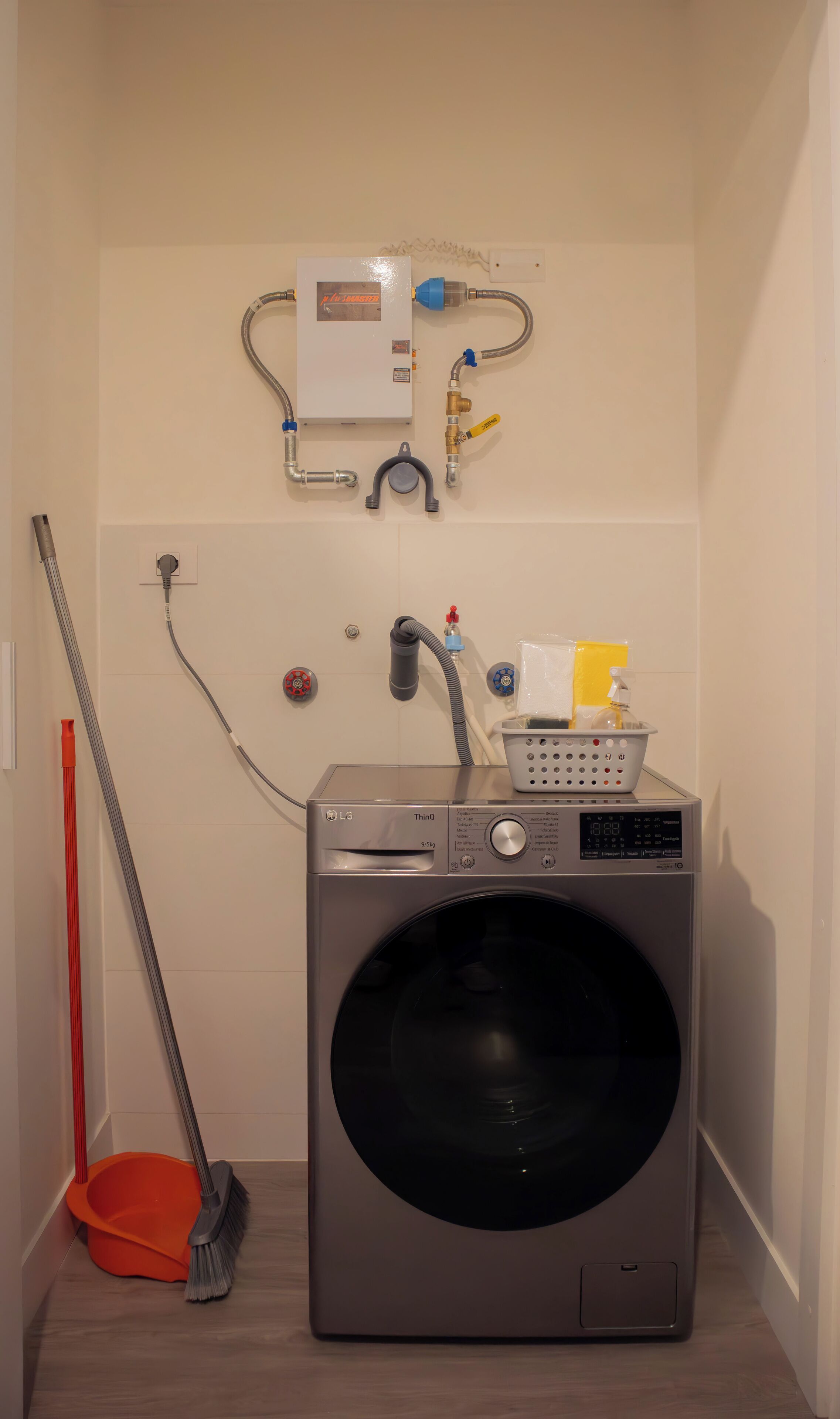 A laundry area with a front-loading washing machine, a hose, and a wall-mounted water heater.
