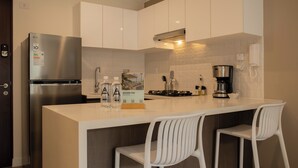 Eine moderne Küche mit einem Edelstahl-Kühlschrank, einem Gasherd und weißen Barhocker.