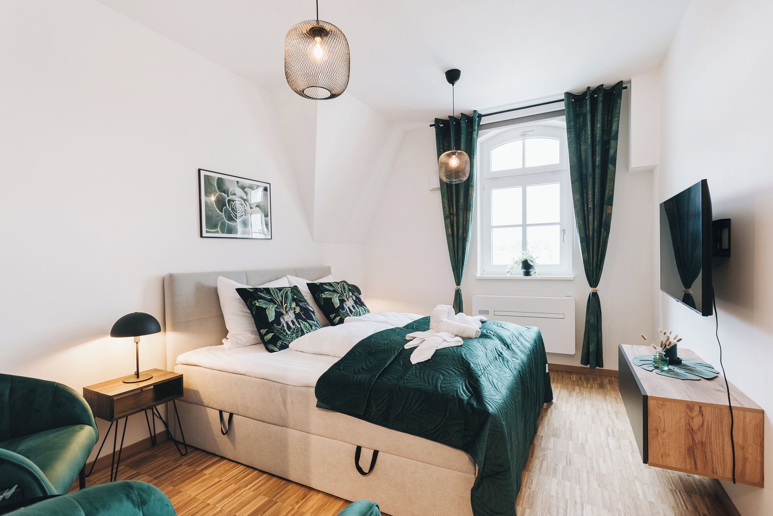 Un dormitorio moderno con cama, mesita de noche, lámpara y televisor.