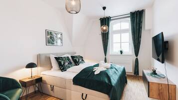 Un dormitorio moderno con cama, mesita de noche, lámpara y televisor.