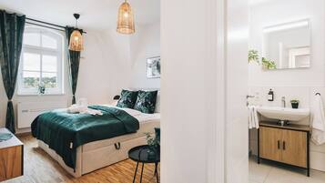 A bedroom with a bed, bedside table, and a hanging light fixture.