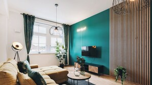 A modern living room with a sofa, a coffee table, a TV, and a potted plant. - Oasis Appart - Wohnen in Dresden (Dresden)