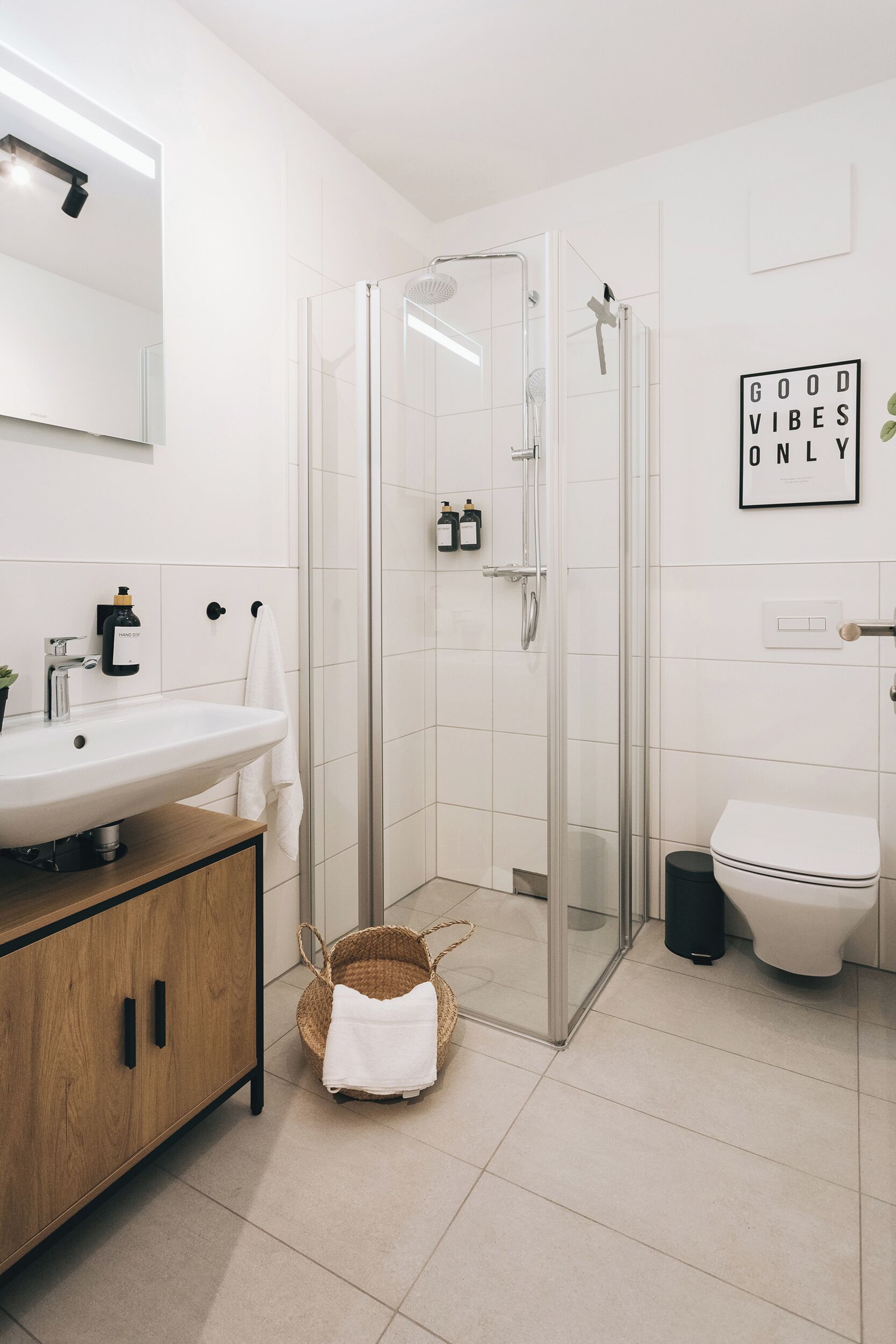 A modern bathroom with a glass shower enclosure, a white sink, and a toilet.