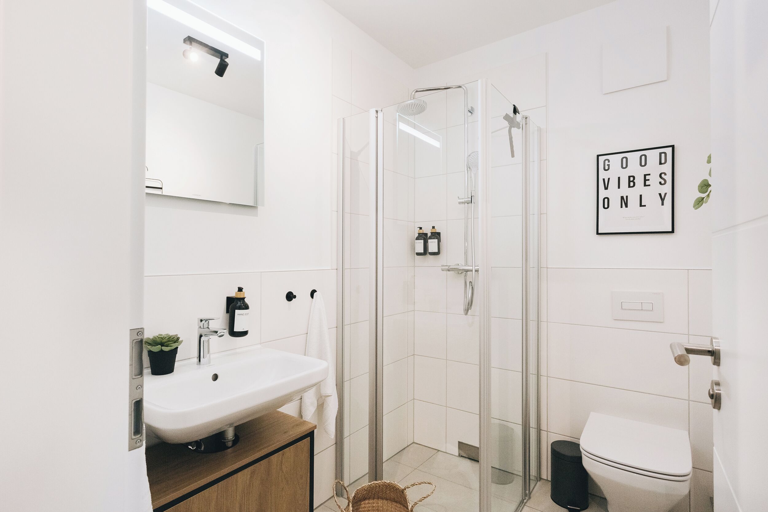 Un baño moderno con cabina de ducha de vidrio, un lavabo e inodoro.
