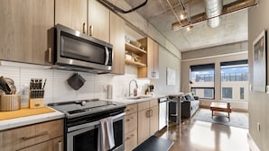 A modern kitchen with wooden cabinets, a stainless steel microwave, and a built-in oven. - Sable 603 - Alcove (Minneapolis)