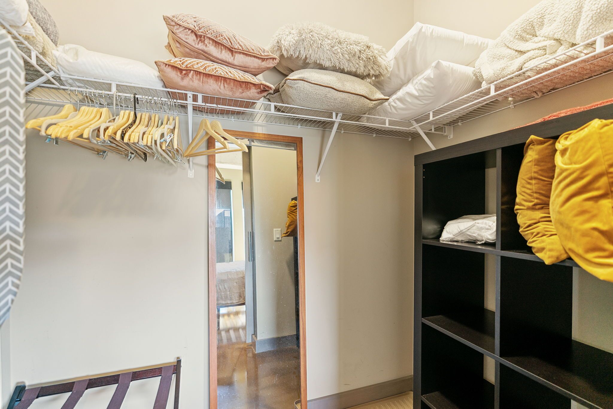 Un dressing avec des vêtements suspendus, des étagères et un lit avec des oreillers.