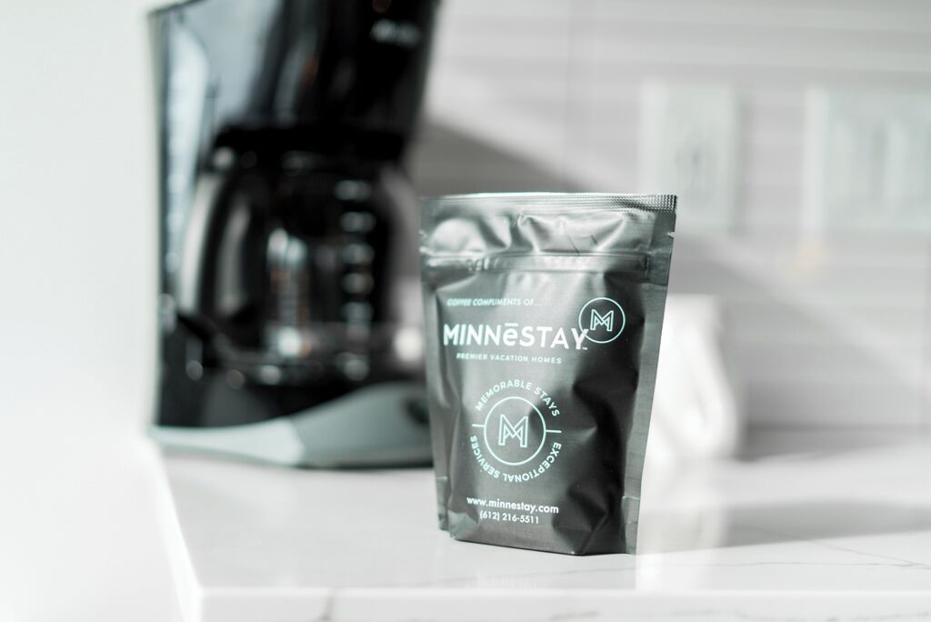 A coffee pod labeled 'MINNESTAY' with a website URL and phone number.