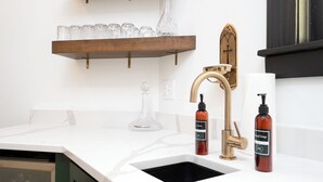 A modern kitchen with a white countertop, a gold faucet, and two soap dispensers. - Lyndale Church Lodge (Minneapolis)