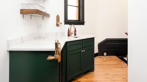 A kitchen with a white countertop, a green cabinet, a wooden floor, and a window with a black frame. - Lyndale Church Lodge (Minneapolis)