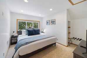 A modern bedroom with a large bed, bedside tables, a desk with a chair, and a window with a view of trees. - Cherokee Park Family Escape (St. Paul)