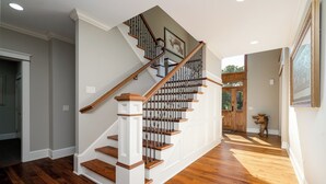 Una escalera de madera con barandilla blanca que conduce a un rellano con una puerta.