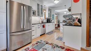 A modern kitchen with stainless steel appliances, white cabinetry, and a wooden floor. - Edina Escape (Minneapolis)