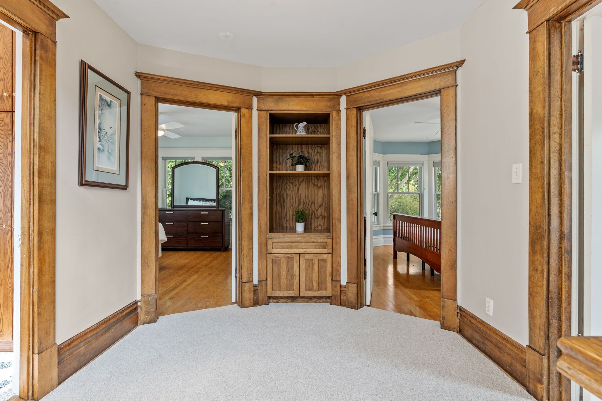 A corner room with a wooden built-in bench, a white wall, and a door leading to another room.