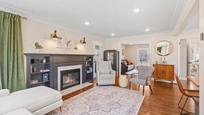 A living room with a fireplace, a sofa, a dining table, and a chair. - Haven in the Heights (Falcon Heights)