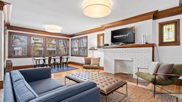 A modern living room with a fireplace, a television, and a dining area with a table and chairs.