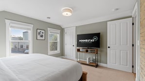 A bedroom with a bed, a television on a stand, and a door.