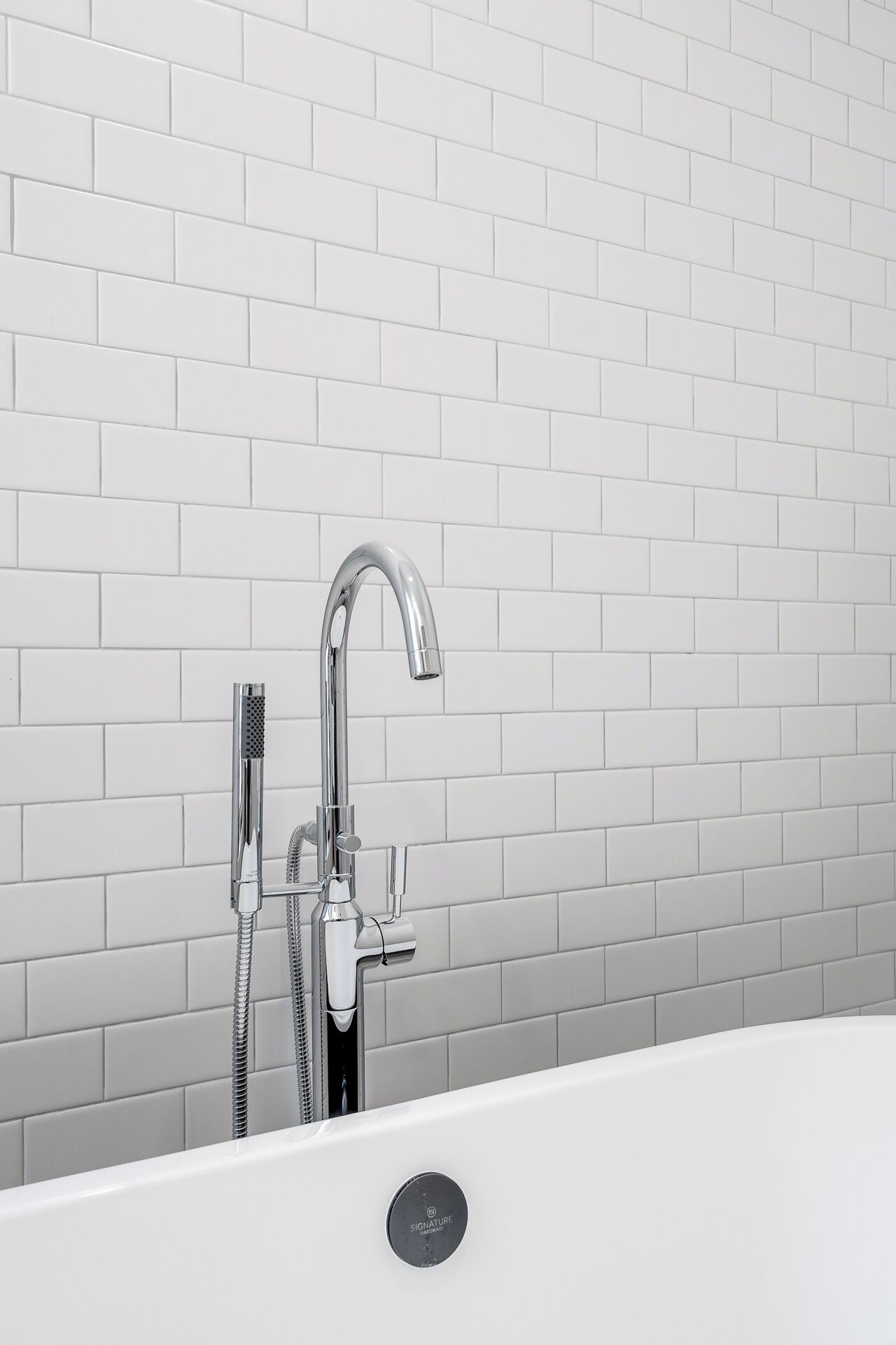 A modern bathroom with a white bathtub, chrome faucet, and shower head.