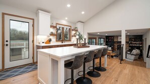 A spacious kitchen with a large island, bar stools, and a view of the outdoors.