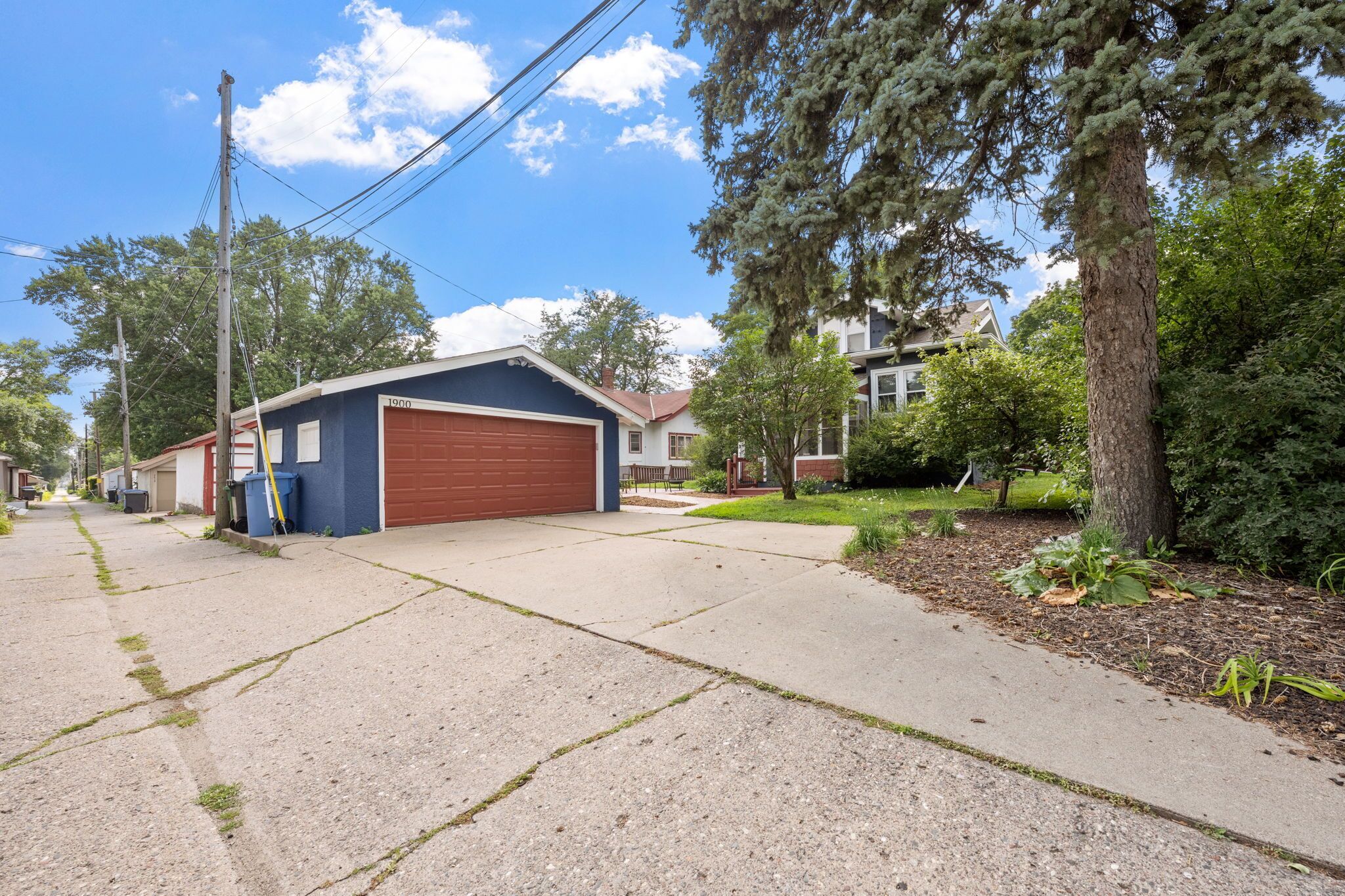 A residential street with a garage, houses, and trees.