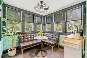 A corner seating area with a cushioned bench, a small round table, and a potted plant. - Lowry Parlour (Minneapolis)