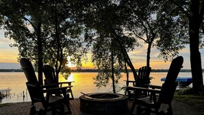 A lakeside seating area with Adirondack chairs and a fire pit. - Lake Pulaski Getaway (Buffalo)