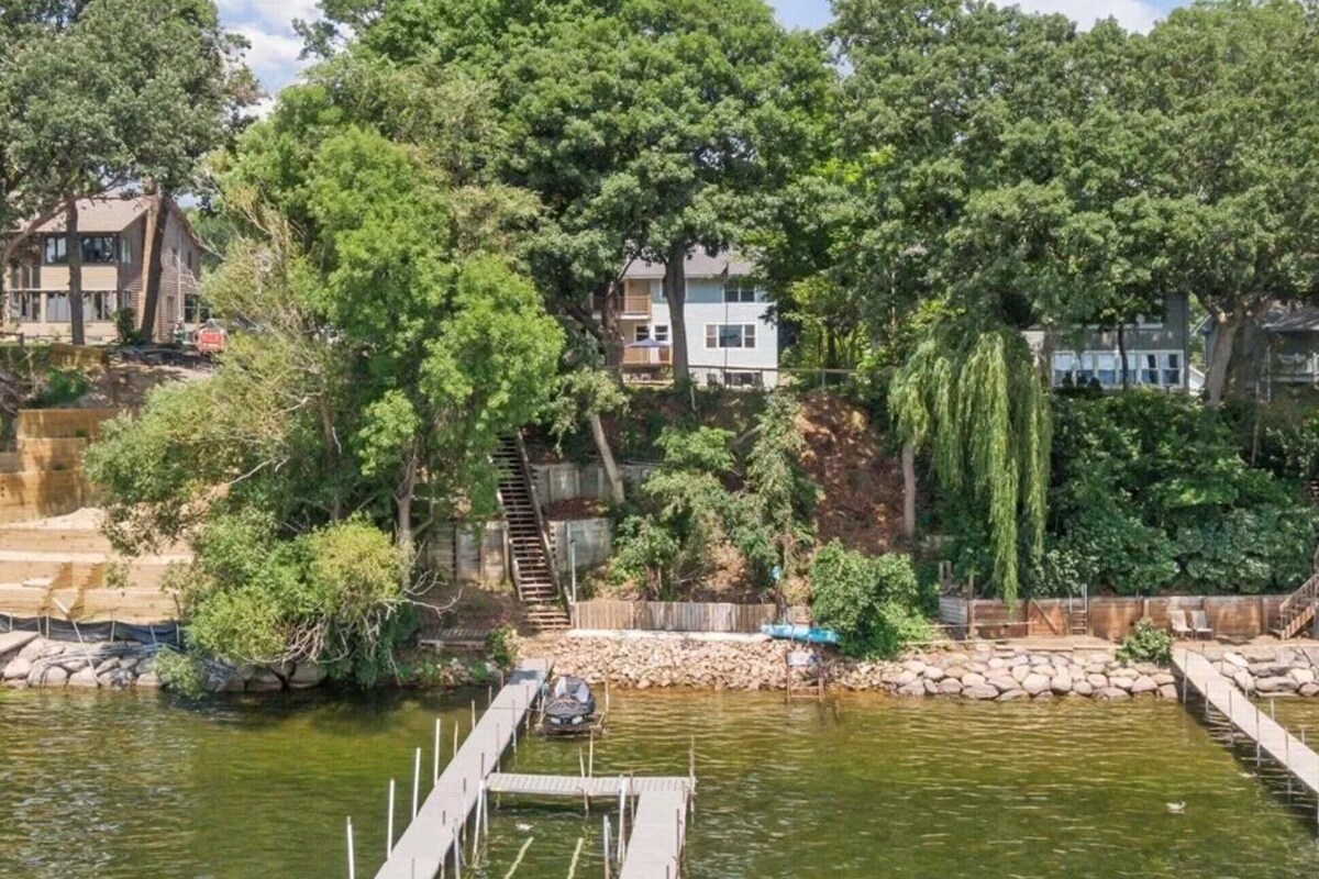 A residential area with a dock extending into a body of water, surrounded by trees and houses.