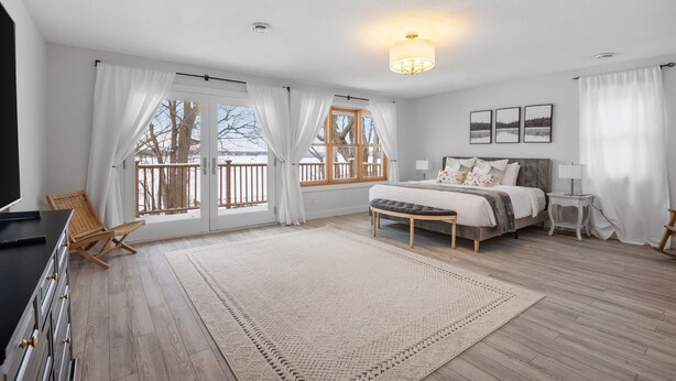 A bedroom with a bed, a desk, a chair, a window with curtains, and a chandelier. - Minnetonka Dream (Wayzata)