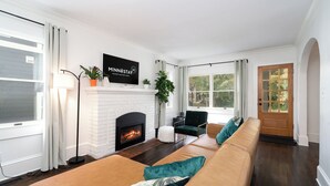 A living room with a fireplace, a sofa set, and a large window. - Fulton Gates (Minneapolis)