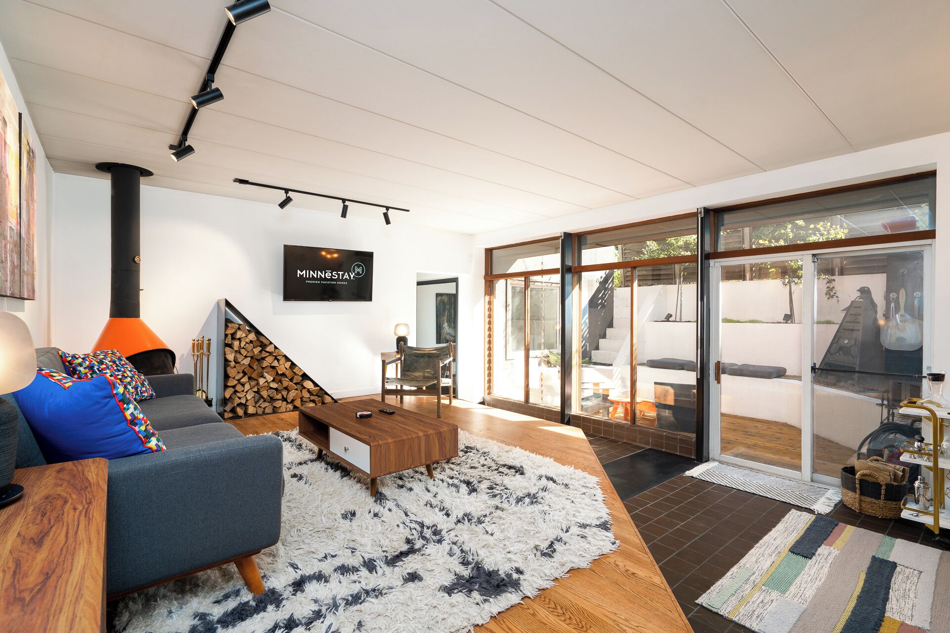 A modern living room with a fireplace, a television, and a large glass door leading to an outdoor area.
