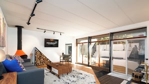 Ein modernes Wohnzimmer mit Kamin, Fernseher und einer großen Glastür zu einem Außenbereich.