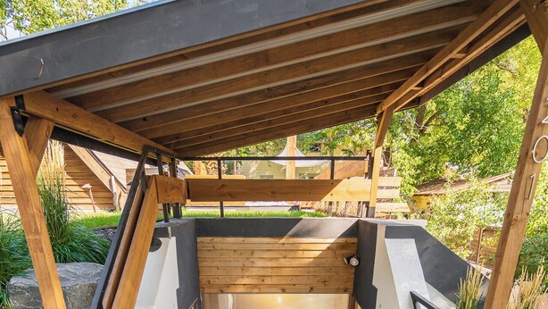 Un rivestimento in legno con una porta, circondato da pareti bianche e un tetto nero.