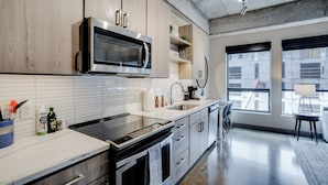 A modern kitchen with stainless steel appliances, wooden cabinets, and a large window providing a view of the city. - Sable 306 - One Bedroom (Minneapolis)