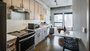 A modern kitchen with stainless steel appliances, wooden cabinets, and a dining area with a table and chairs. - Sable 302 - Alcove (Minneapolis)