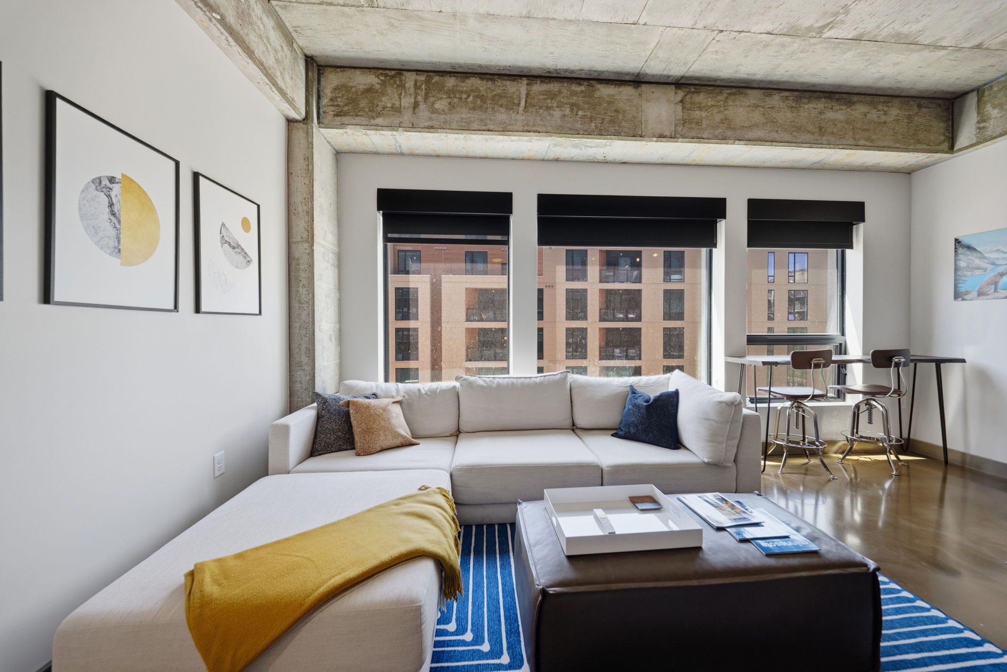 Ein modernes Wohnzimmer mit Ecksofa, Couchtisch und Kunstwerken an den Wänden.