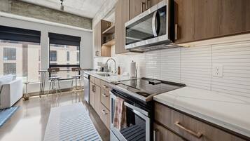 A modern kitchen with wooden cabinets, a stainless steel microwave, and a built-in oven.
