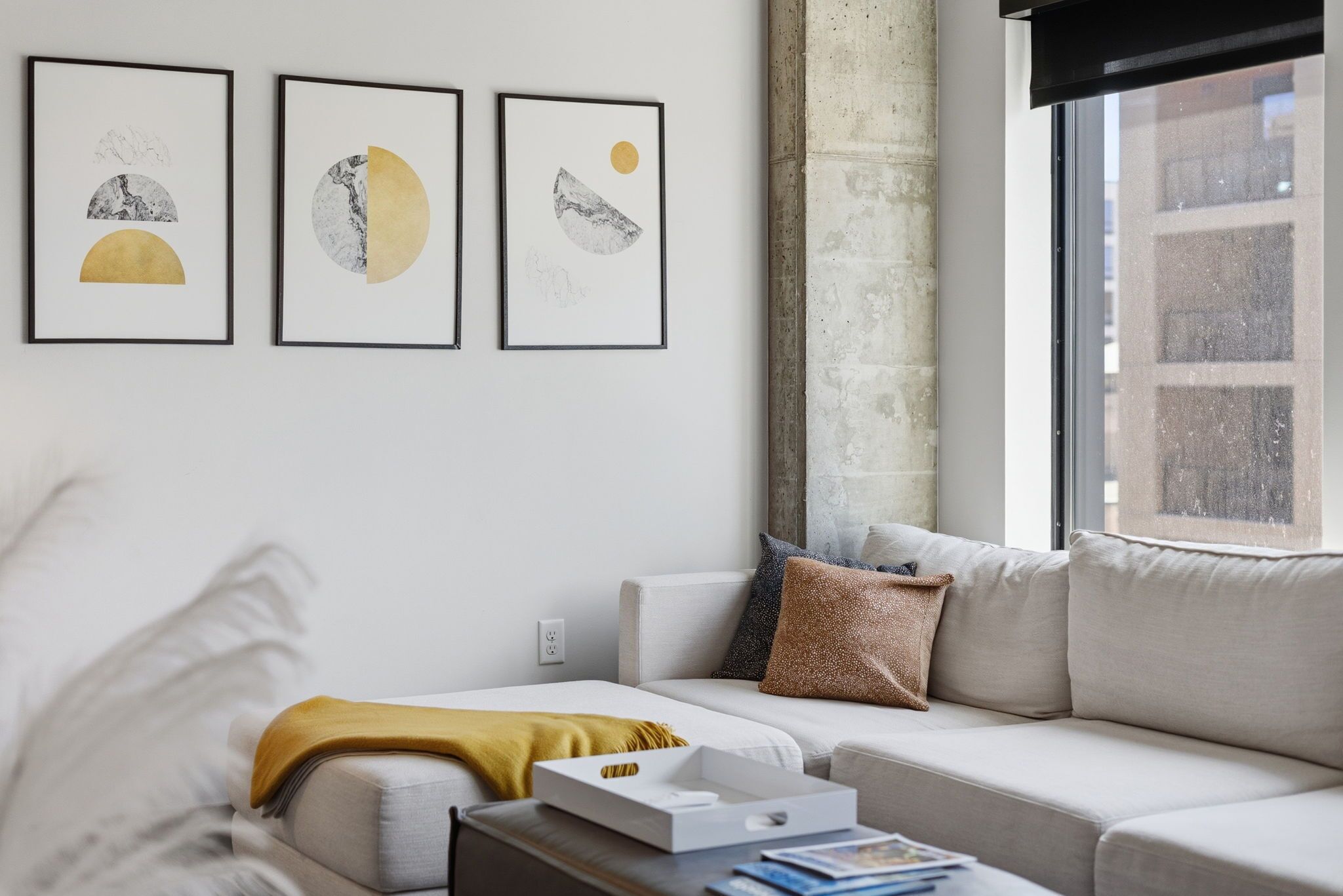 Una sala de estar moderna con un sofá, una mesa de centro y tres obras de arte enmarcadas en la pared.