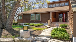 A modern two-story house with a red door, large windows, and a stone pathway leading to the entrance.