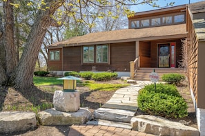 A modern two-story house with a red door, large windows, and a stone pathway leading to the entrance.
