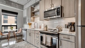 A modern kitchen with wooden cabinets, stainless steel appliances, and a large window. - Sable 409 - One Bedroom (Minneapolis)
