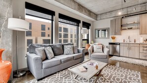 A modern living room with a grey sofa, a patterned rug, and a coffee table with a book and remote. - Sable 409 - One Bedroom (Minneapolis)