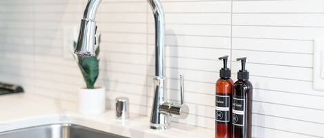 A modern kitchen sink with a chrome faucet and two soap dispensers.