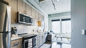A modern kitchen with stainless steel appliances, wooden cabinets, and a large window providing natural light. - Sable 206 - Alcove (Minneapolis)