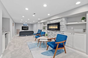Una sala de estar moderna con chimenea, televisor y sillones azules.